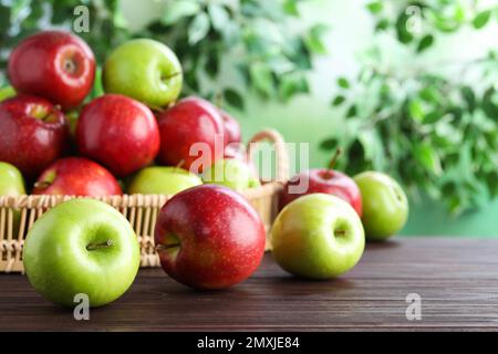 Saftige rote und grüne Äpfel in Korbschale auf Holztisch im Freien Stockfoto