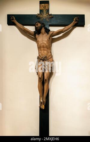 Jesus Christus kreuzigte auf dem hölzernen Kreuz an der Wand im Infantado-Turm, Museum von Beato de Liebana, Potes, Kantabrien, Spanien Stockfoto