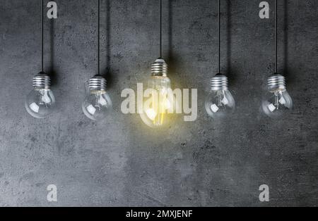 Ideenkonzept. Glühbirne u. a. auf grauem Hintergrund Stockfoto