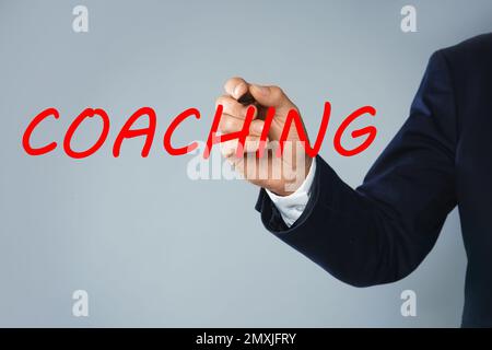 Business Trainer schreibt das Wort Coaching auf einem virtuellen Bildschirm, Nahaufnahme Stockfoto