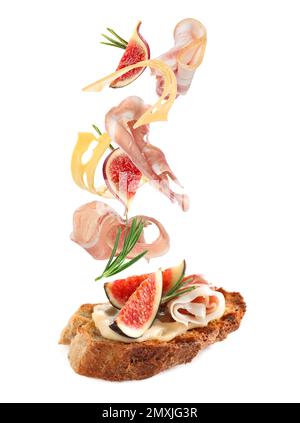 Leckeres Bruschetta mit fliegenden Zutaten auf weißem Hintergrund Stockfoto