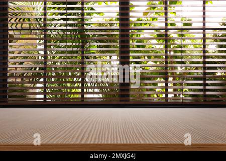 Holztisch und -Fenster mit Jalousien im Hintergrund Stockfoto