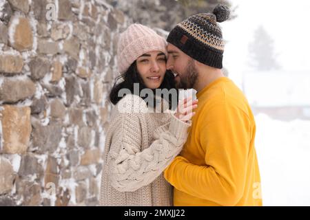 Schönes Paar, das an verschneiten Tagen draußen warme Pullover und Hüte trägt. Wintersaison Stockfoto