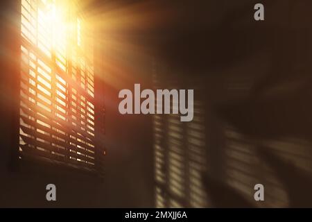 Die Sonne scheint durch die Fensterläden im Zimmer Stockfoto