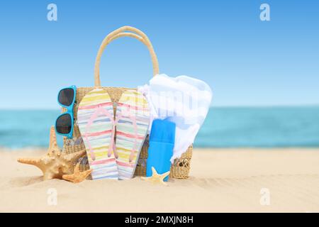 Tasche und Strandgegenstände auf Sand nahe dem Meer, Platz für Text Stockfoto