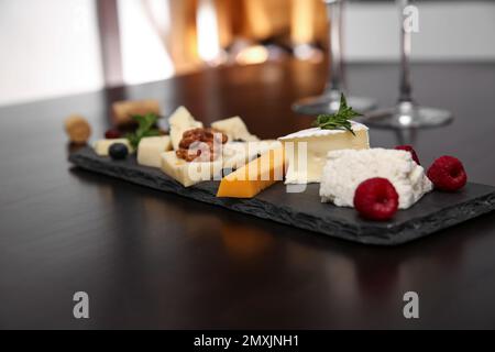 Verschiedene Arten von köstlichem Käse mit Beeren und Nüssen auf dem Tisch Stockfoto