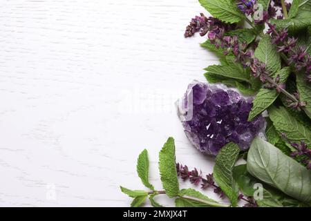 Amethyst Edelstein und Heilkräuter auf weißem Holztisch, Platz für Text Stockfoto