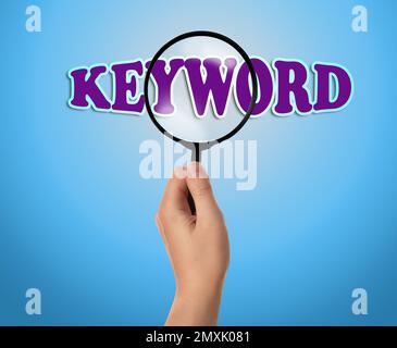Frau, die das Wort Schlüsselwort durch eine Lupe sieht, Nahaufnahme Stockfoto