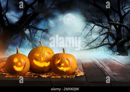 Unheimliche Jack O Lantern Kürbisse umgeben von mystischem Nebel bei Vollmond an Halloween. Platz für Text Stockfoto