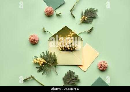 Ostern-Hintergrund. Mimosa- und Freesia-Blumen, Wachteleier, mintgrüne Umschläge und Farbpapier auf grünem Hintergrund. Flach liegend, über Kopf, knurrt Stockfoto