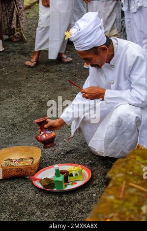 Hindu-Priester mit Korb und Teller bereitet Angebote zu, buddhistischer hinduistischer Tempelkomplex Pura Ulun Danu Bratan, Candi Kuning, Bratansee, Bali, Indonesien Stockfoto