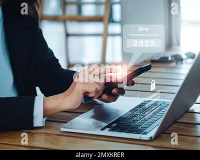 Zwei-Stufen-Authentifizierung (2FA) Konzept. 2023, Verifizierungscode- und Schlüsselsymbol-Warnung auf dem Smartphone, während der Computer zur Passwortbestätigung verwendet wird, Stockfoto