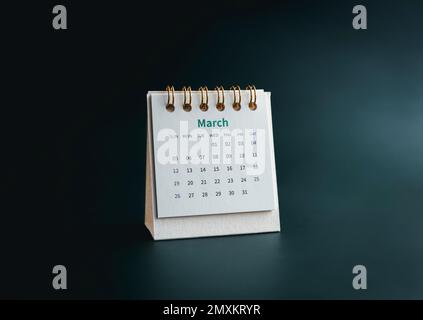 Ein Kalender-Desk für den 2023. März, an den der Organisator planen und erinnern kann, isoliert auf dunkelgrünem Hintergrund, minimalistisch. Weißer kleiner Tischkalender mit TH Stockfoto