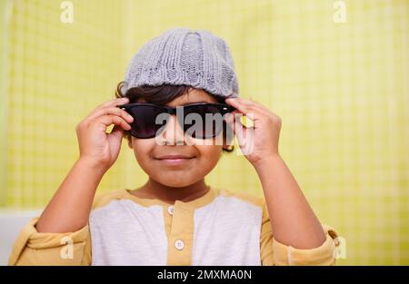 Er ist ein cooler Typ. Porträt eines süßen kleinen Jungen mit Sonnenbrille und Mütze. Stockfoto
