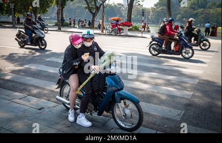 Ein junges Paar hält auf seinem Motorrad, um sich ein Smartphone im Stadtzentrum von Hanoi, Vietnam, anzusehen. Stockfoto