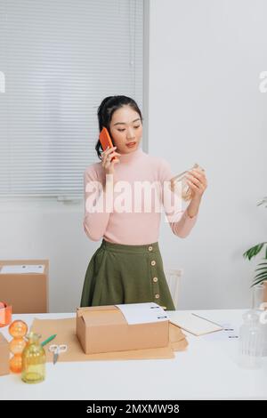 Frauen, die freiberuflich tätig sind, und Verpackungskartons, die online an Kunden geliefert werden. Stockfoto