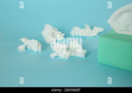 Gebrauchte Papiertücher und Schachtel auf hellblauem Hintergrund Stockfoto