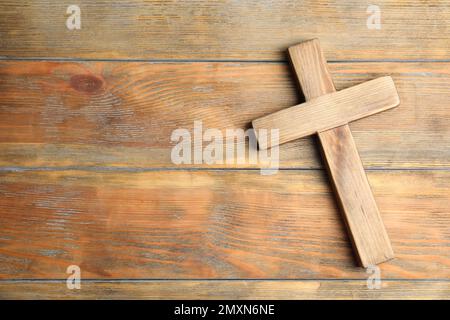 Christliches Kreuz auf Holzhintergrund, Draufsicht mit Platz für Text. Religionskonzept Stockfoto