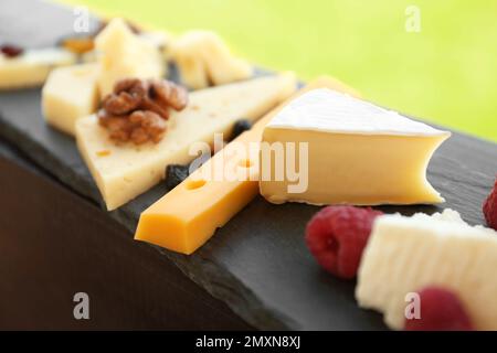 Verschiedene Arten von köstlichem Käse und Snacks auf Schieferteller, Nahaufnahme Stockfoto