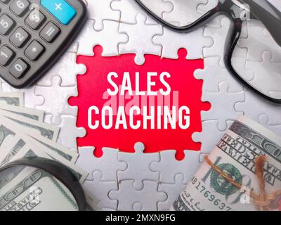 Weißes Puzzle mit dem Wort SALES COACHING auf rotem Hintergrund. Geschäftskonzept. Stockfoto