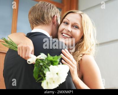 Paare, Umarmungen und Blumen für die Liebe, Valentinstag oder Date, um eine Beziehung im Freien zusammen zu genießen. Glückliche Frau, die ihren Freund umarmt und weiß hält Stockfoto