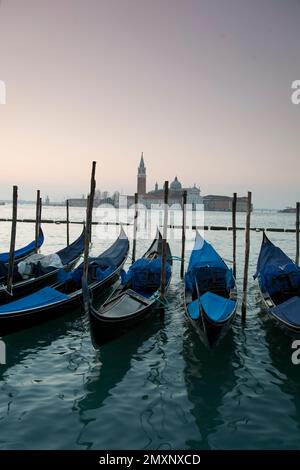 Sonnenaufgang vom Markusplatz mit Blick über festgemachte Gondeln in Richtung San Giorgio Maggiore, Venedig, Italien. Stockfoto