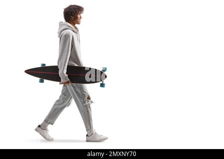 Profilaufnahme eines afroamerikanischen Kerls mit einem Longboard, der isoliert auf weißem Hintergrund läuft Stockfoto
