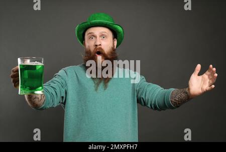 Bärtiger Mann mit grünem Bier auf grauem Hintergrund. St. Patrick's Day-Feier Stockfoto