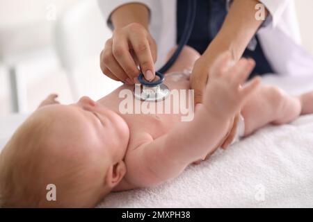 Doktor untersucht süßes Baby mit Stethoskop drinnen, Nahaufnahme. Gesundheitsfürsorge Stockfoto