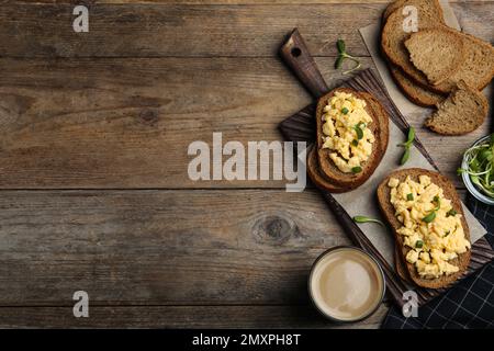 Leckere Rührei-Sandwiches auf einem Holztisch, flach liegend. Platz für Text Stockfoto