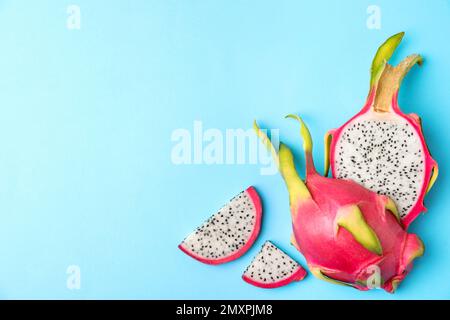 Köstliche geschnittene Drachenfrucht (Pitahaya) auf hellblauem Hintergrund, flach liegend. Platz für Text Stockfoto