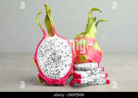 Köstliche geschnittene und ganze Drachenfrüchte (Pitahaya) auf einem grauen Tisch Stockfoto