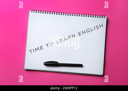 Öffnen Sie das Notizbuch mit dem Text Time to Learn English und Stift auf pinkfarbenem Hintergrund, Draufsicht Stockfoto