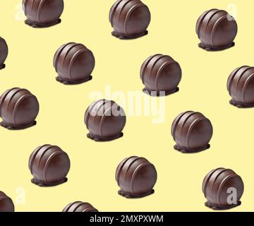 Leckere Schokoladenbonbons auf blassgelbem Hintergrund. Musterkonstruktion Stockfoto