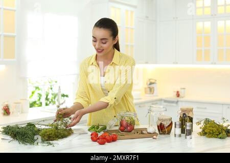 Frau, die eingelegtes Gemüse am Tisch in der Küche zubereitet Stockfoto