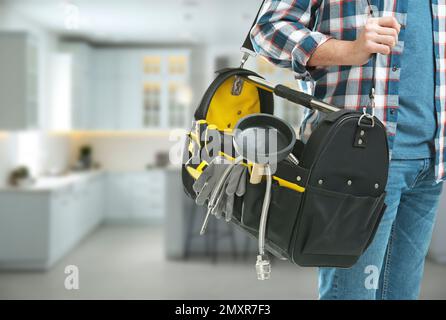 Junger Klempner mit Werkzeugtasche in der Küche, Nahaufnahme. Platz für Text Stockfoto