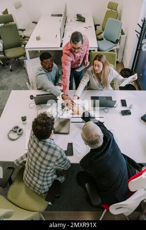 Das Marketing-Team gibt sich einen Handschlag für seine Bemühungen und seinen Erfolg im Büro Stockfoto