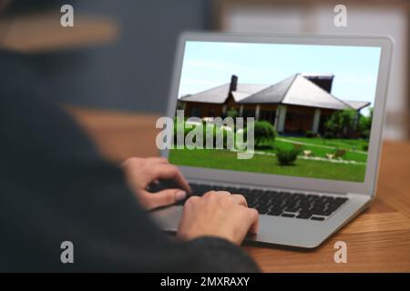 Frau wählt online ein neues Haus mit Laptop oder Immobilienmakler, die am Tisch arbeiten, Nahaufnahme Stockfoto