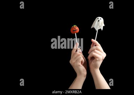 Frau mit leckeren Kuchenwürfeln und Platz für Text auf schwarzem Hintergrund, Nahaufnahme. Halloween-Feier Stockfoto