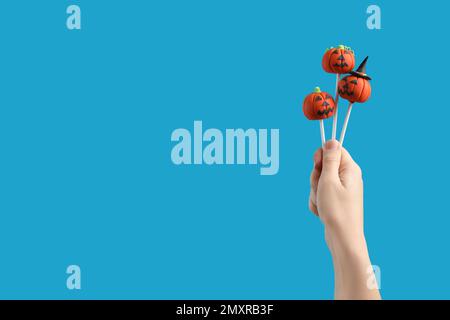 Frau mit köstlichen Kürbiskuchen und Platz für Text auf hellblauem Hintergrund, Nahaufnahme. Halloween-Feier Stockfoto