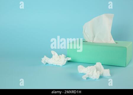 Gebrauchte Papiertücher und Schachtel auf hellblauem Hintergrund. Platz für Text Stockfoto
