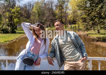 Fröhliche attraktive Mann und Frau mit viel Spaß im Freien, erzählen Witze, genießen warmen Tag. Foto in voller Länge Stockfoto