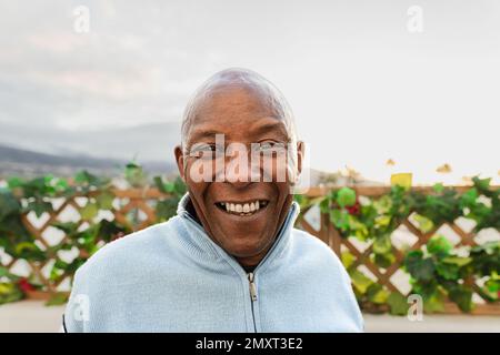 Glücklicher afrikanischer Senior-Mann, der vor der Kamera lächelt, auf der Terrasse des Hauses Stockfoto