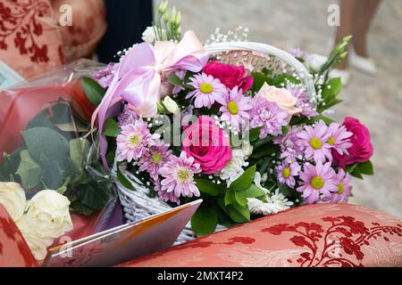 Ein riesiger Strauß aus Rosen, Gänseblümchen, Chrysanthemen in einem weißen Korb mit Schleife. Stockfoto