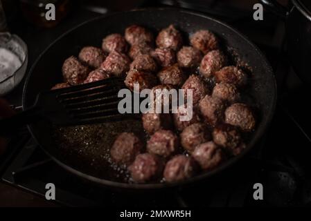 Fleischbällchen in einer Bratpfanne. Fleischbällchen machen. Dunkler Hintergrund. Stockfoto