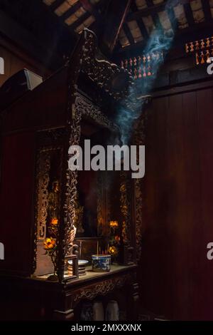 Räucherrauch in einem Tempel mit Lichtstrahl auf einem Altar im buddhistischen Tempel. Stockfoto