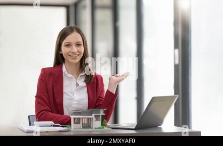 Asiatische Geschäftsfrau, die einen Deal macht, ein Haus oder eine Wohnung im Büro zu kaufen, Hausversicherungs-Konzept Stockfoto