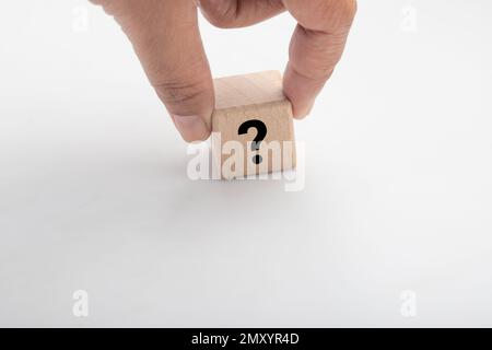 Eine Hand hält einen Holzblock mit einem Fragezeichen auf weißem Hintergrund Stockfoto