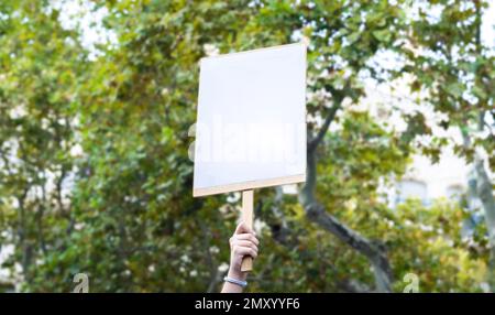 Leeres Banner, um die gewünschte Nachricht zu schreiben. Mit einem leeren Plakat aus Pappe, um den Sieg während eines Protests zu feiern. Poster einer Demonstration. Platz für Stockfoto