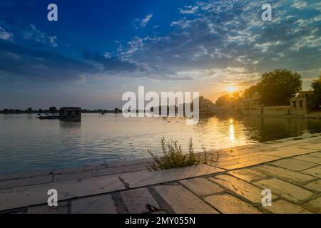 Schöner Sonnenuntergang am Gadisar Lake, Jaisalmer, Rajasthan, Indien. Untergehende Sonne und bunte Wolken am Himmel mit Blick auf den Gadisar See. Stockfoto